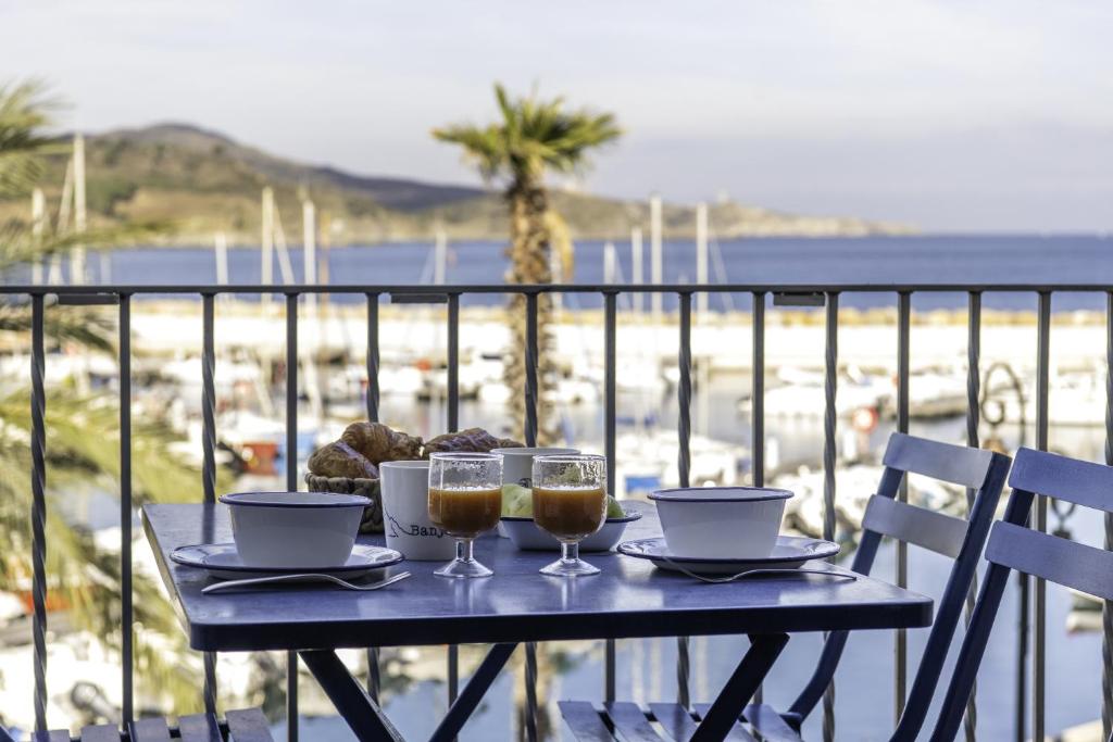 a table with two glasses of wine and a view of the beach at Résidence la Grande Voile in Banyuls-sur-Mer