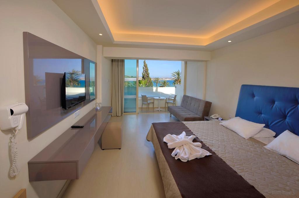 a bedroom with a bed and a tv and a couch at Nelia Beach Hotel & Spa in Ayia Napa