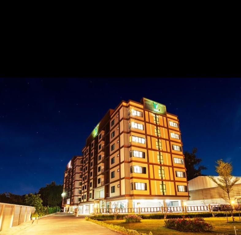 a tall building is lit up at night at V-twin Condo Donjan in Chiang Mai