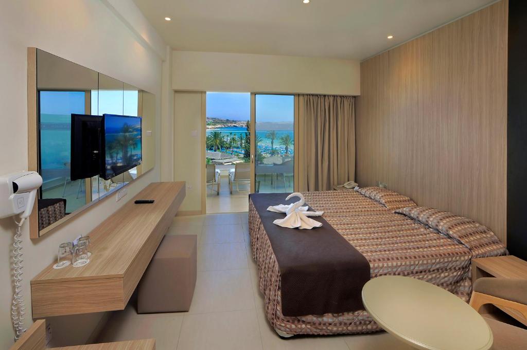 a hotel room with a large bed and a flat screen tv at Nelia Beach Hotel & Spa in Ayia Napa