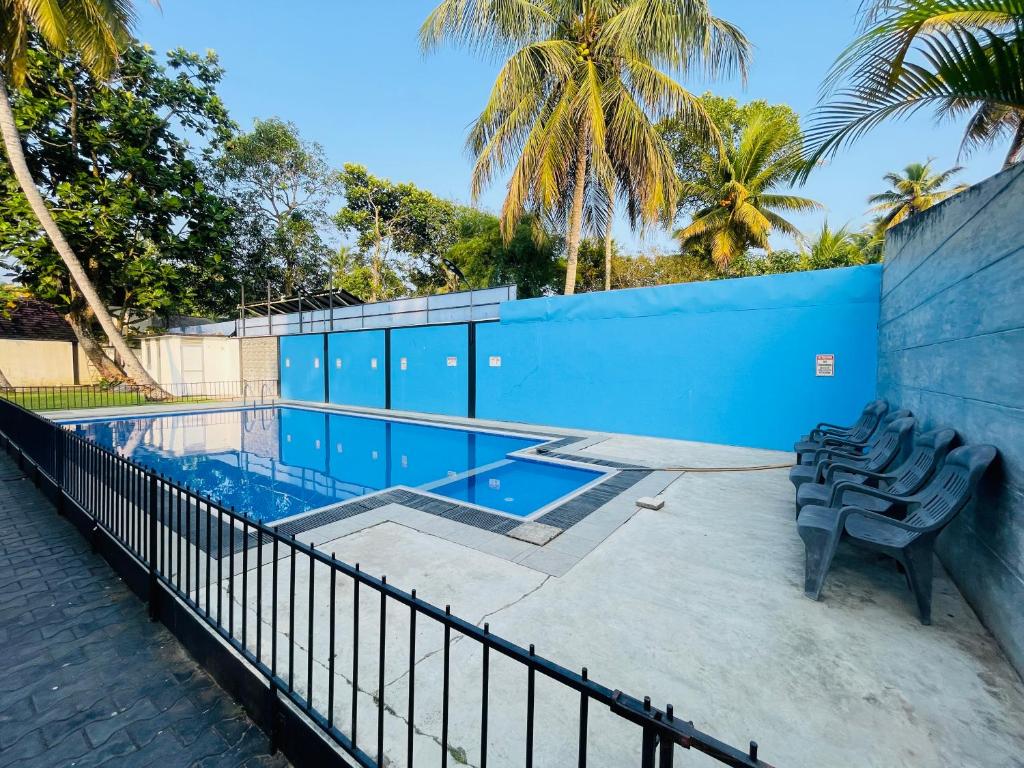 a swimming pool with chairs next to a fence at Kapuwatta Pool Villa in Weligama