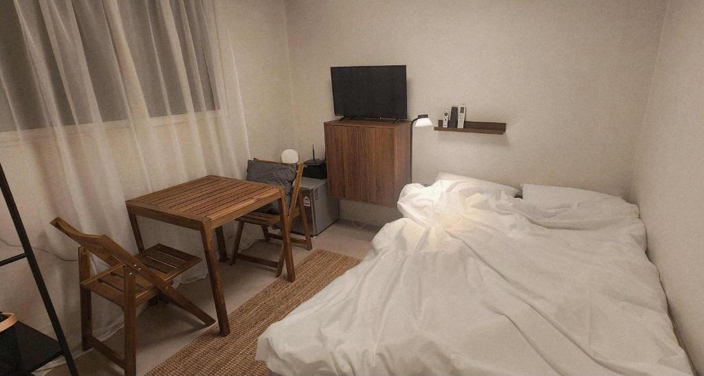 a bedroom with a bed and a table and a tv at 낙원파크포도홈 in P'ungnyŏn-gol