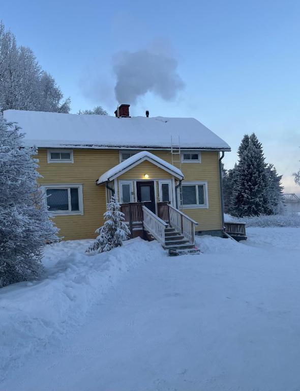 a yellow house with snow on the ground at Apartment MUMMOLA in Rovaniemi