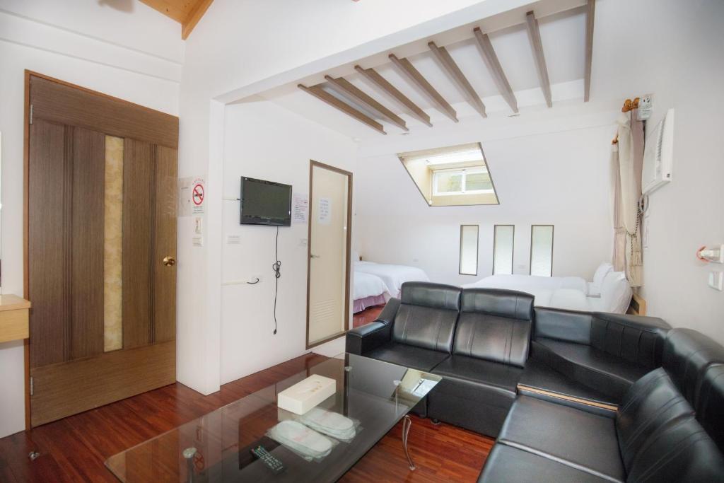 a living room with a black couch and a tv at Natural Residence B&amp;B in Tai&#39;an