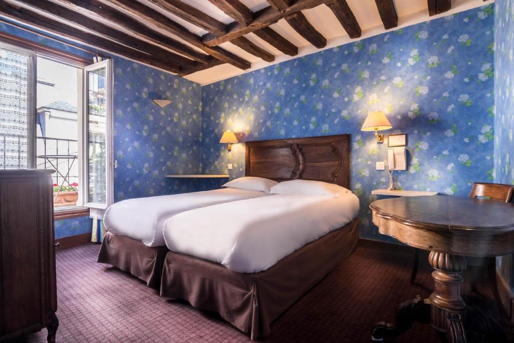 a bedroom with a bed, a desk, and a painting on the wall at Hotel du Lys in Paris