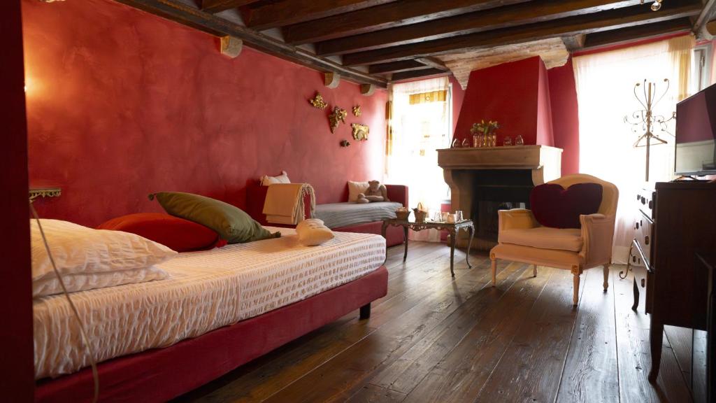 a bedroom with red walls and a bed and a fireplace at Locanda Al Cappello in Udine