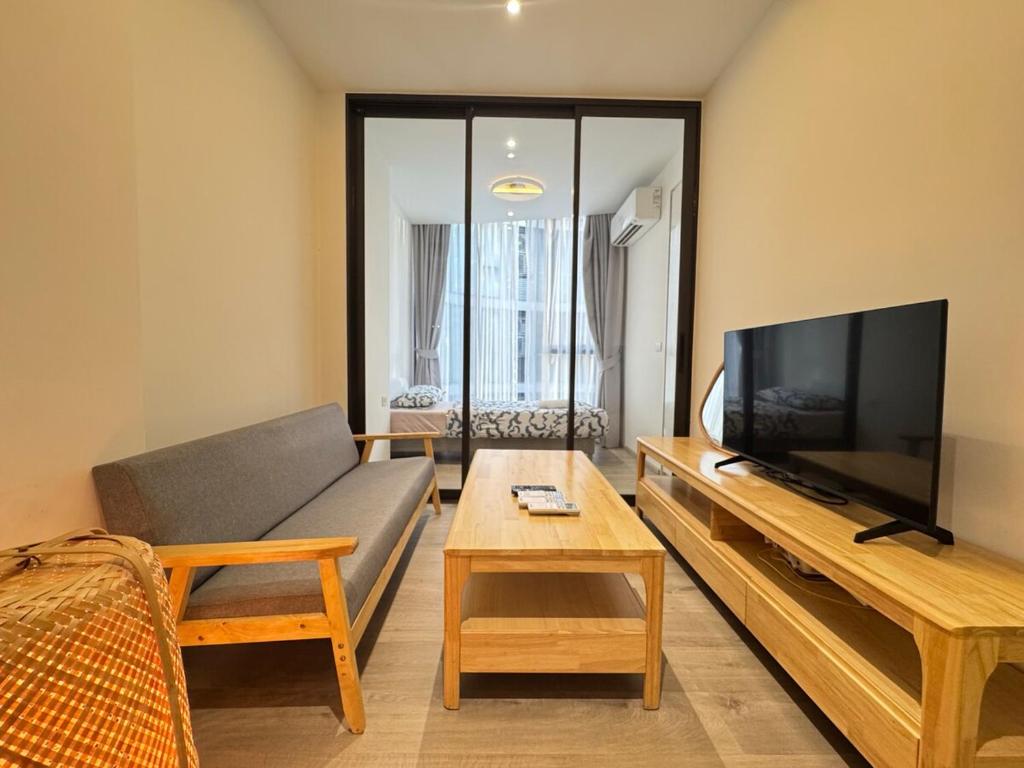 a living room with a couch and a flat screen tv at Fynn Bangkok Asoke Condo in Bangkok