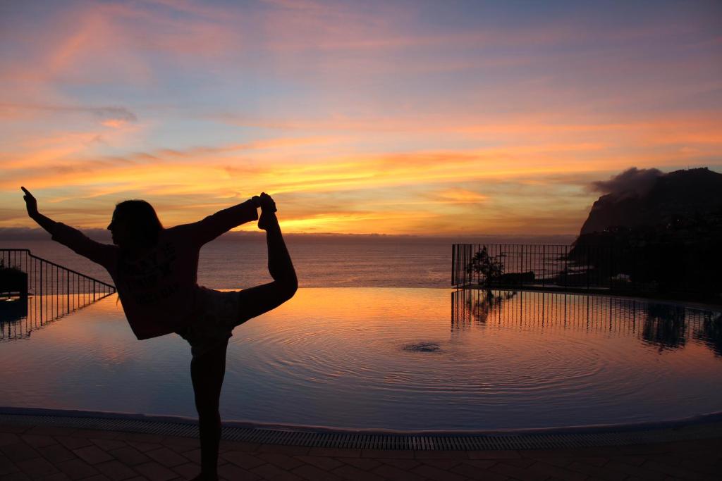 una mujer haciendo una pose de yoga frente a una piscina en Atlantic Ocean View Apartment, en Funchal