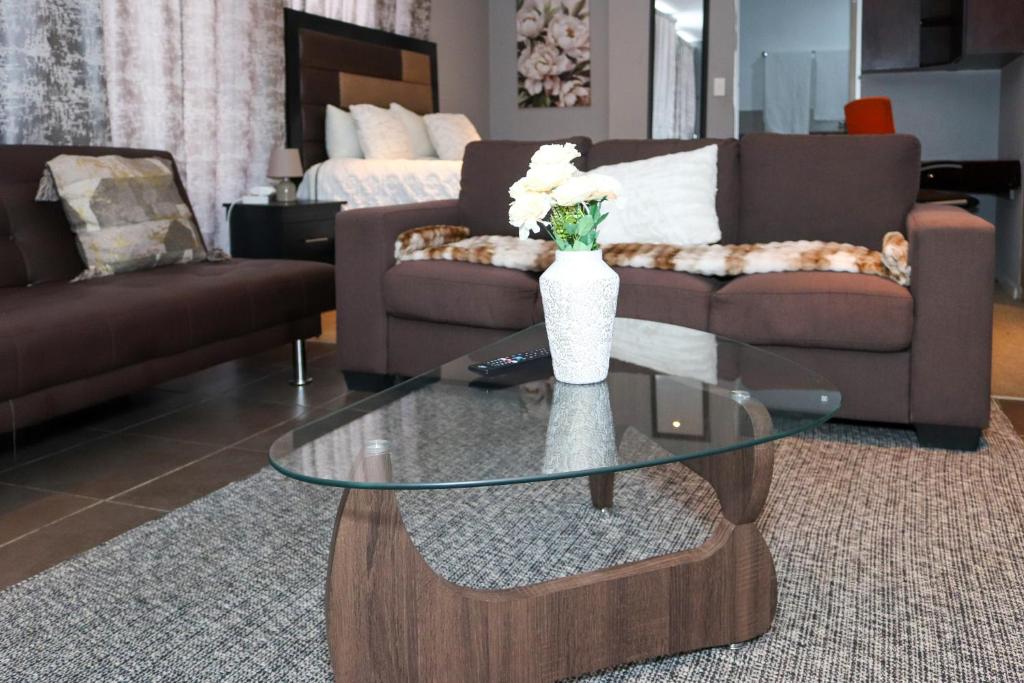 a living room with a glass table with a vase with flowers at The Orange Corner III in Johannesburg