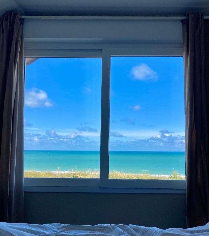a bedroom window with a view of the beach at Villa Denise Petit Gîte in Barneville-Carteret