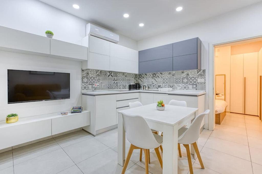 a white kitchen with a white table and chairs at Floriana Cozy Haven in Il-Furjana