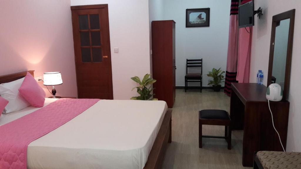 a bedroom with a white bed and a desk and a chair at New Rani Inn in Negombo