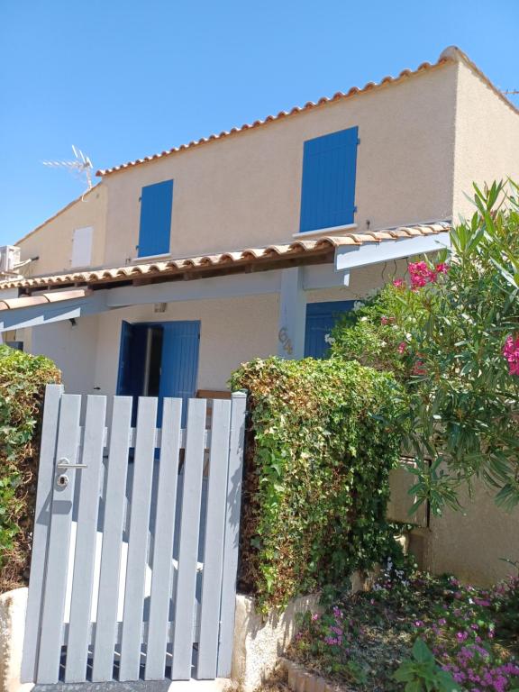 a white fence in front of a house with flowers at maison 100 m de la plage à pieds in Portiragnes