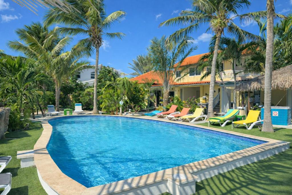 a swimming pool in front of a house with palm trees at Casalina Garden 2 blocks to Palm Beach & Kitesurfing school in Palm-Eagle Beach