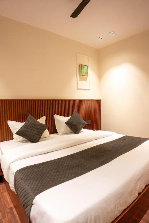 a bedroom with a large white bed with black pillows at Comfy GK Residency in New Delhi