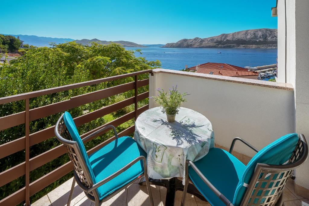 a table and chairs on a balcony with a view of the water at Double Rooms Jasna with Sea View in Baška