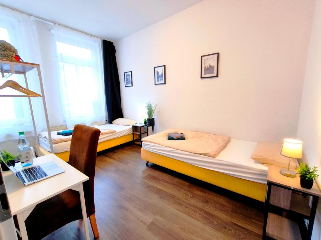 a room with two beds and a desk with a laptop at Schwert City Loft S41 2 BAD 2 WC 4 Schlafzimmer in Verden