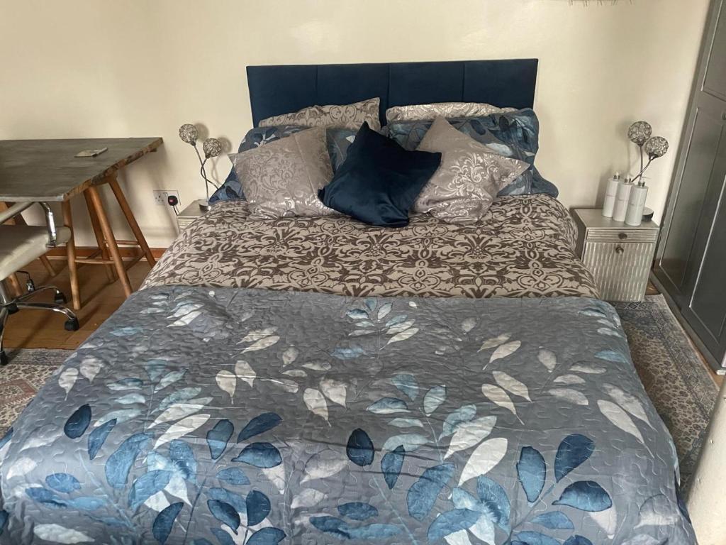 a bed with a blue and white comforter and pillows at Fenland Gallery in Whittlesey