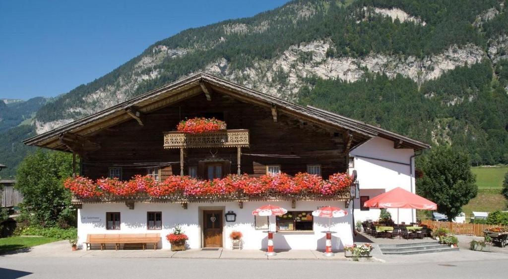 a building with flowers on it with a mountain at Camping Seehof in Kramsach