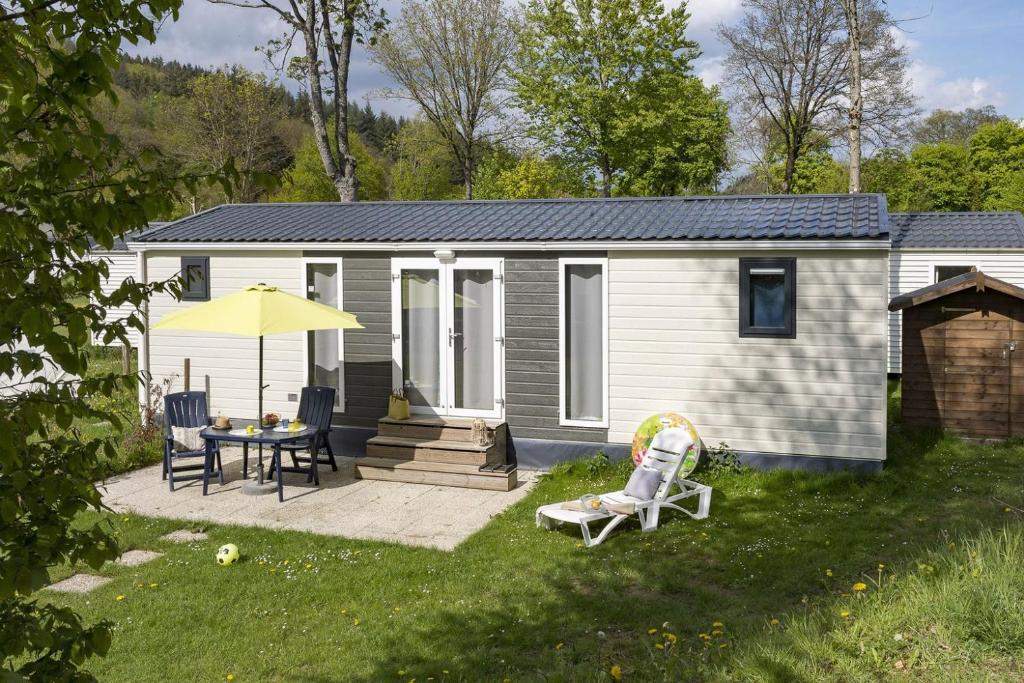 a small house with a patio and a table and chairs at Cottage Jardenne 6p 3Bdrms in Grupont