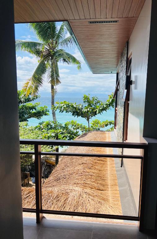 ein Zimmer mit Blick auf eine Palme und das Meer in der Unterkunft Seajour Beach Resort in Ginatilan
