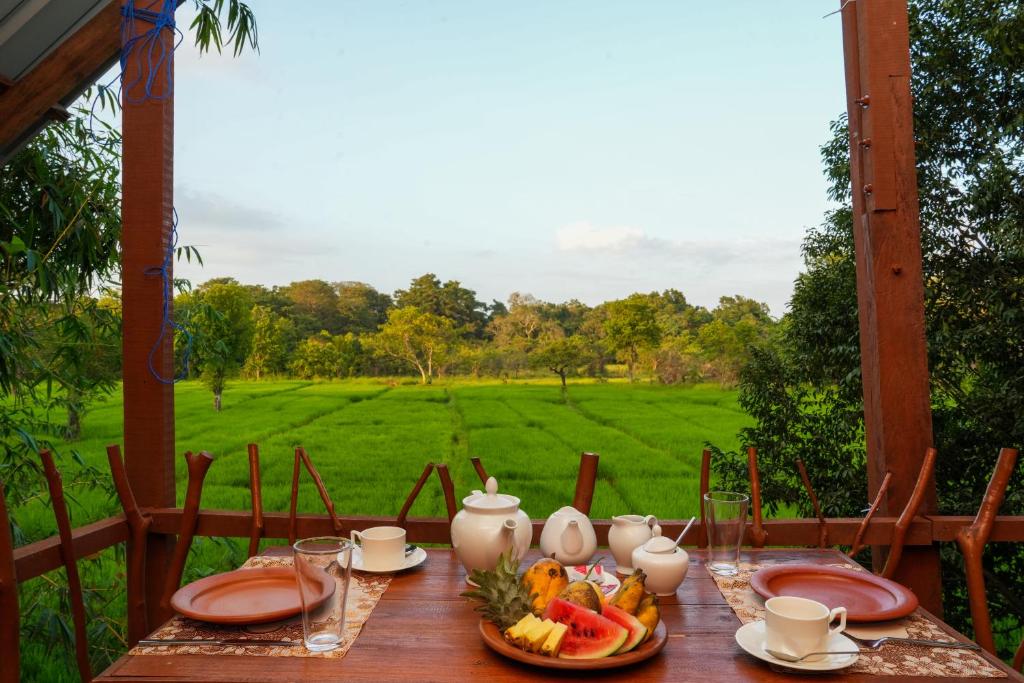 a wooden table with plates of food and fruit on it at Comfort Treehouse Pidurangala in Dambulla
