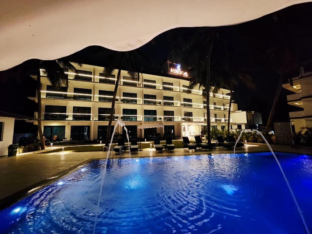 a hotel with a swimming pool in front of a building at La Vida Colva Beach Resort in Colva
