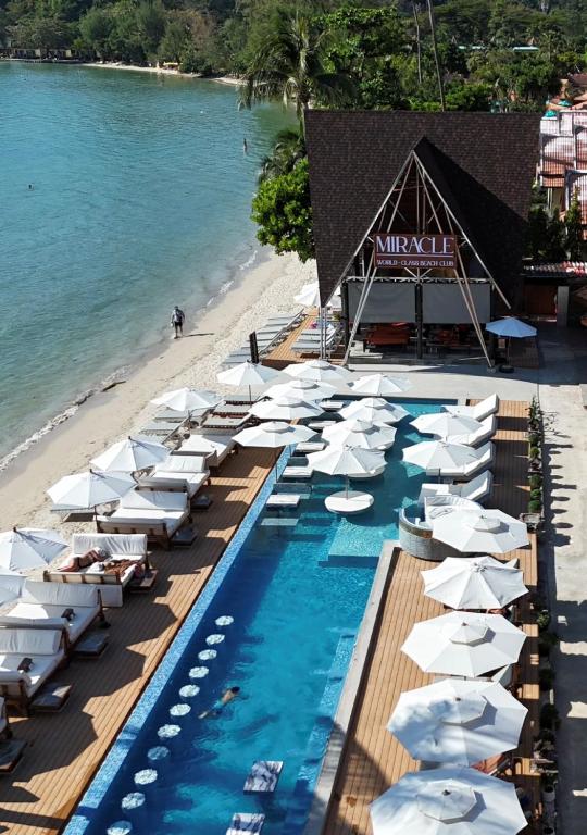 a pool with white umbrellas and a beach at Koh Chang Resort in Ko Chang