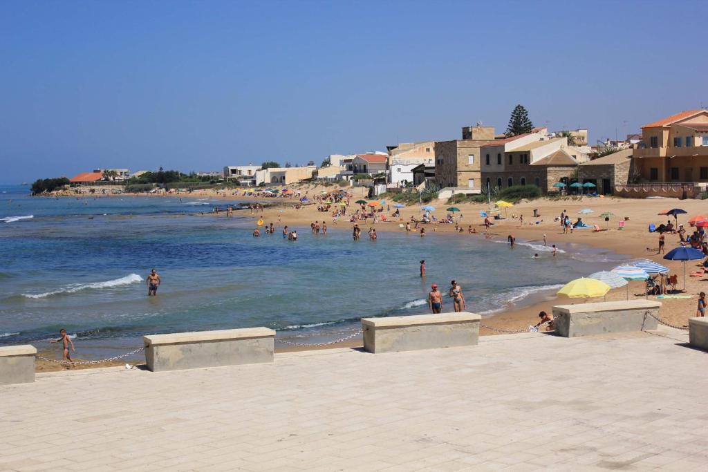 a beach with a bunch of people in the water at Appartamenti Pomelia Punta Secca in Punta Secca