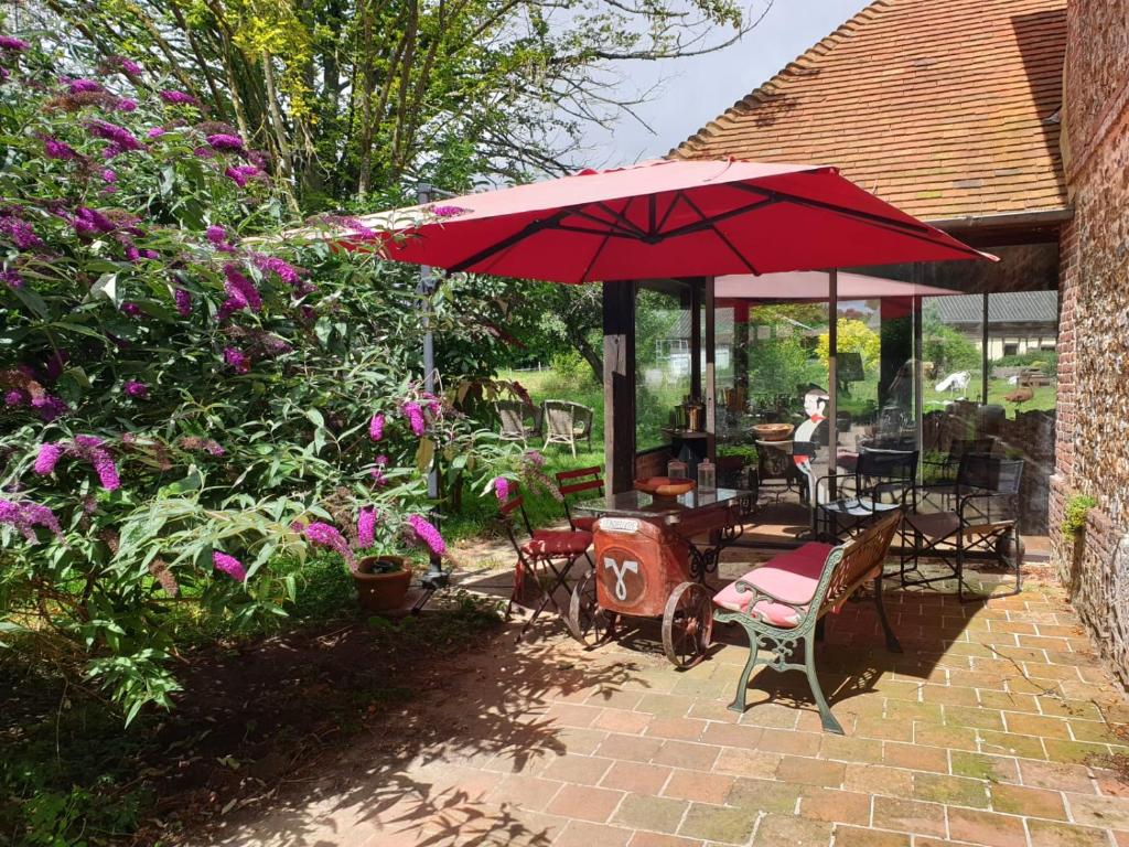 a patio with a red umbrella and a table and chairs at Domaine de La Siaule in Saint-Germain-dʼAunay