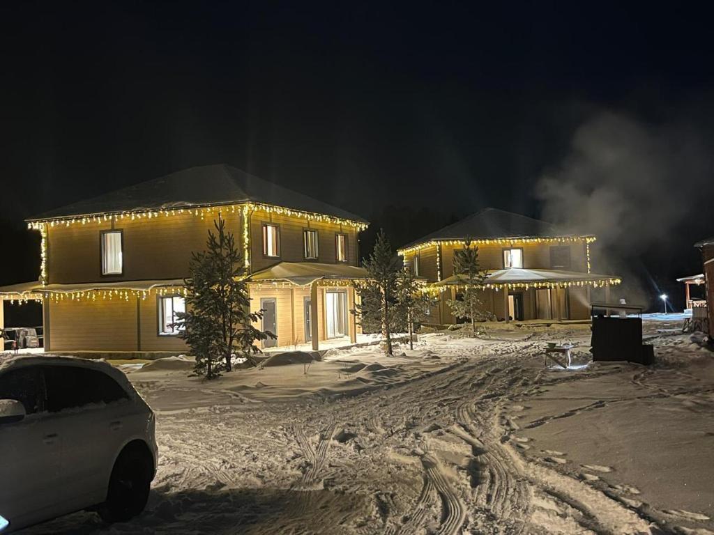 a house with a car parked in front of it in the snow at Forest Club Burabay in Zhezdi