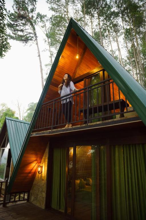 a woman standing on the balcony of a house at Monsoon Cabana Ella in Ella