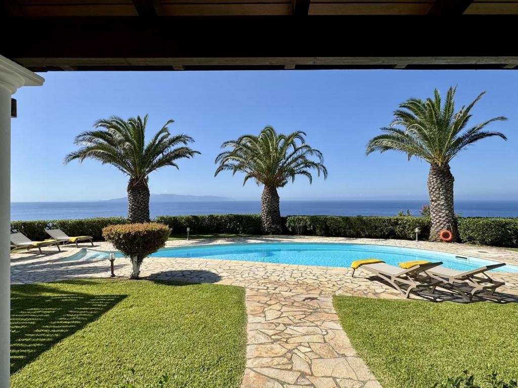 a swimming pool with palm trees in the background at Villa Ermis Spartia Kefalonia in Spartià