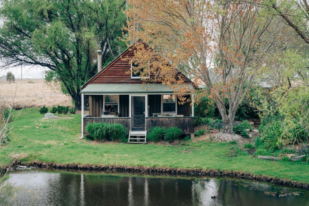 a small house sitting on the side of a river at Breathe Glenrock Gardens in Tenterfield