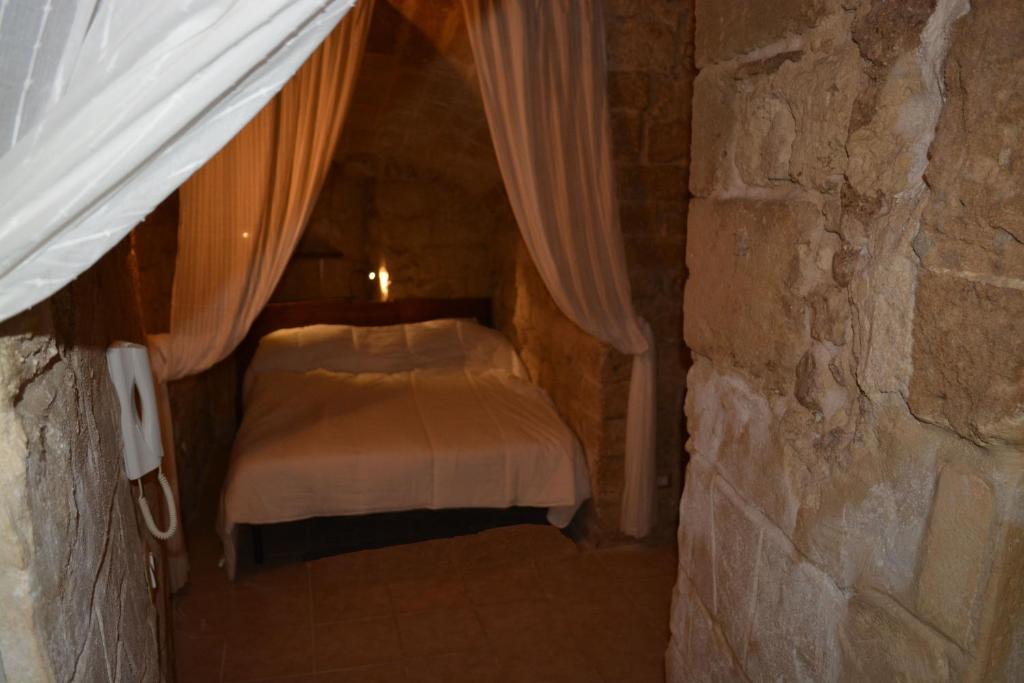 バーリにあるPalazzo di Città Flatの小さなベッドルーム(石壁のベッド付)