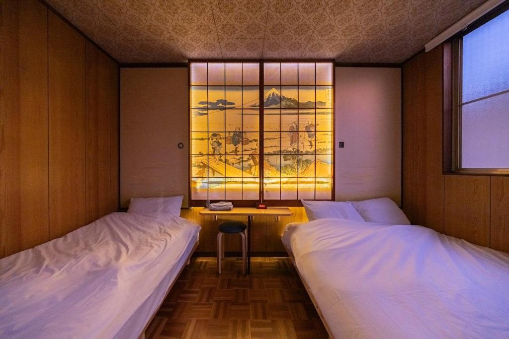 two beds in a room with a window at Soresta INN Shinozaki in Tokyo