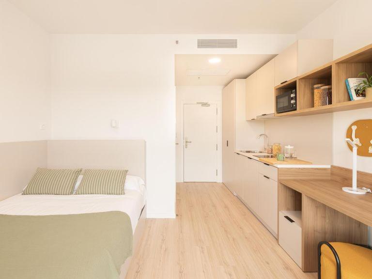 a small bedroom with a bed and a kitchen at Canvas Sabadell Llac in Sabadell