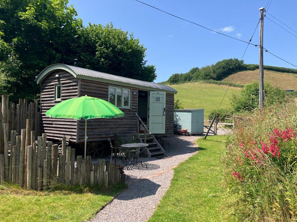 a green umbrella in front of a tiny house at Steam and Stars Luxury Glamping in Williton