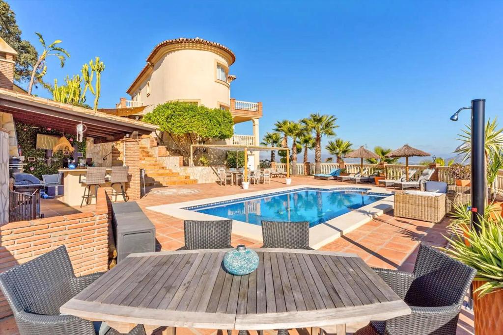 a patio with a table and chairs and a pool at Montaña Mimosa B&B in Alhaurín el Grande