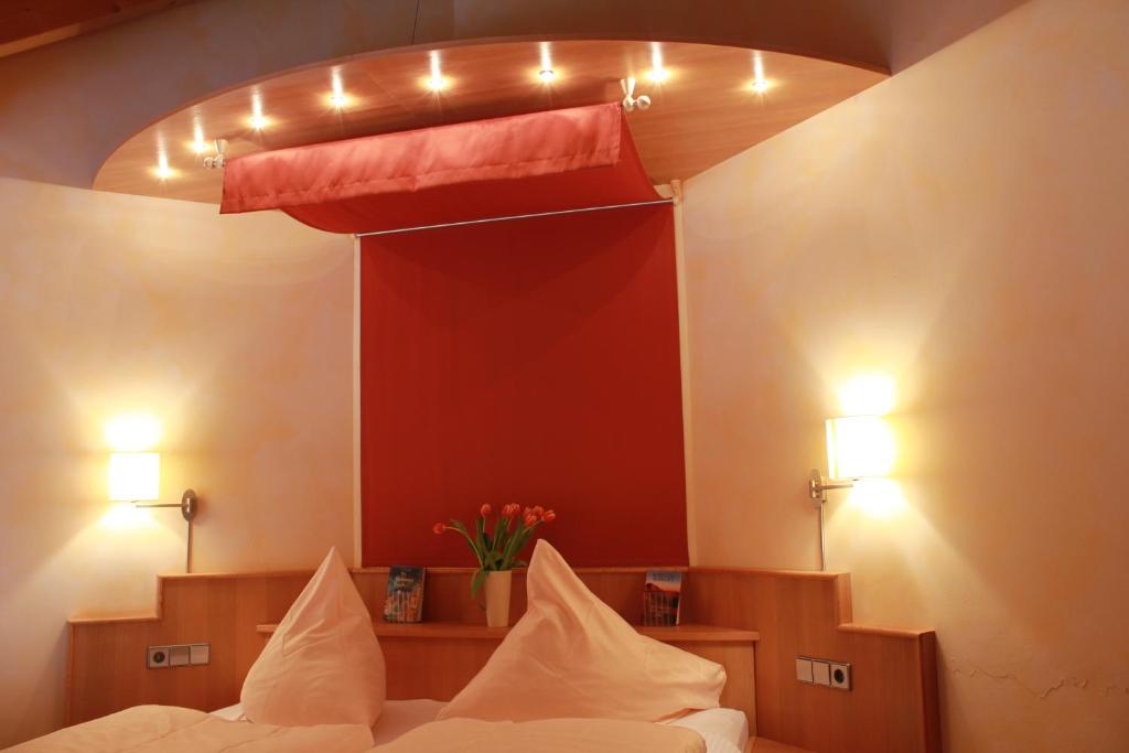 a bedroom with a bed and a red wall with lights at Hotel-Restaurant Fröhlich in Kaiserslautern