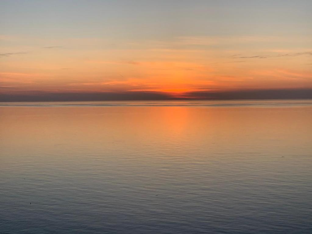 an orange sunset over the ocean with the sky at Tini's Apartment in Gonio