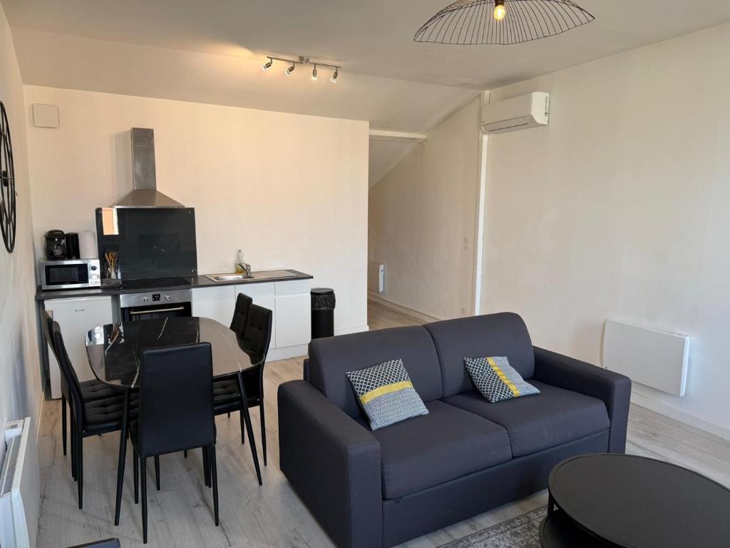a living room with a blue couch and a table at LE DALLAS - 1 chambre, 1 canapé-lit, 1er étage, parking, 10min Canal du Midi in Castelsarrasin