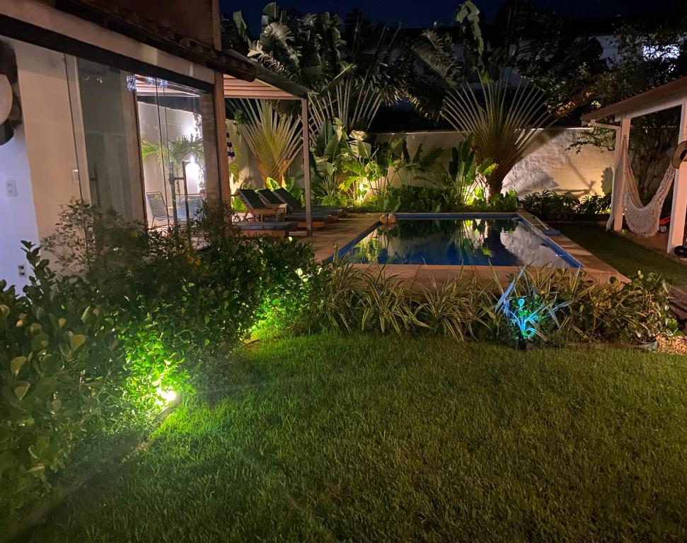 a backyard with a pool with lights in the grass at Casa Mediterrânea Geribá in Búzios