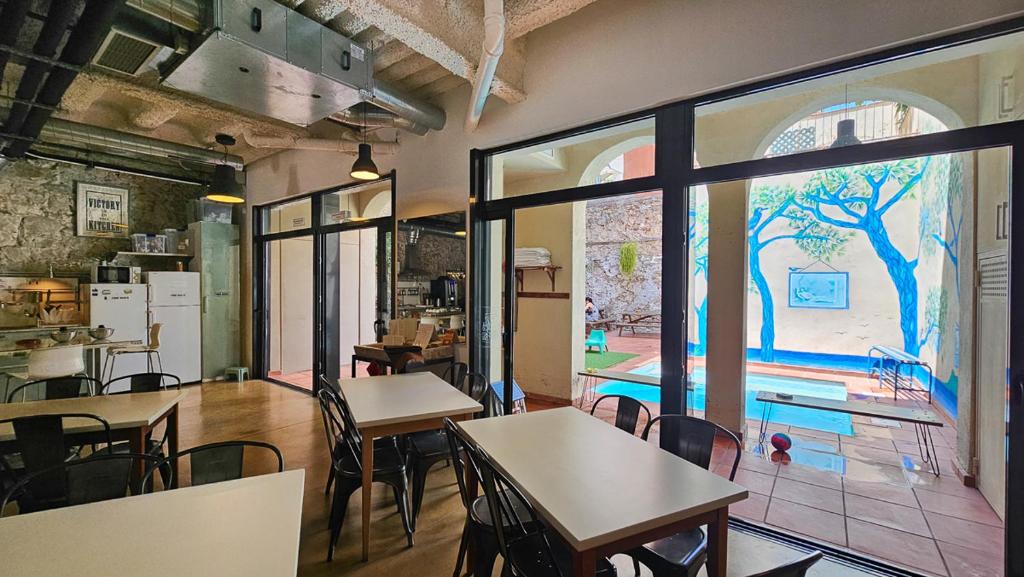 a room with tables and chairs and a large window at Ten To Go Hostel in Barcelona