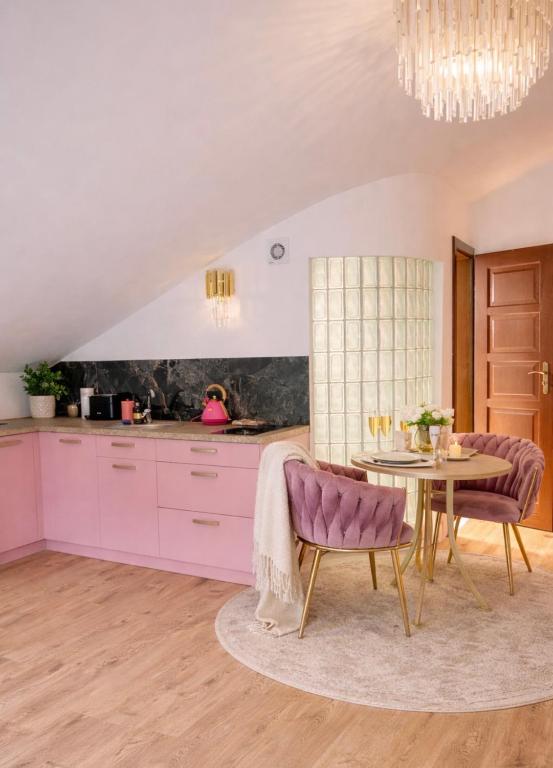 a kitchen with pink cabinets and a table with purple chairs at Apartament Premium Cichowo in Cichowo
