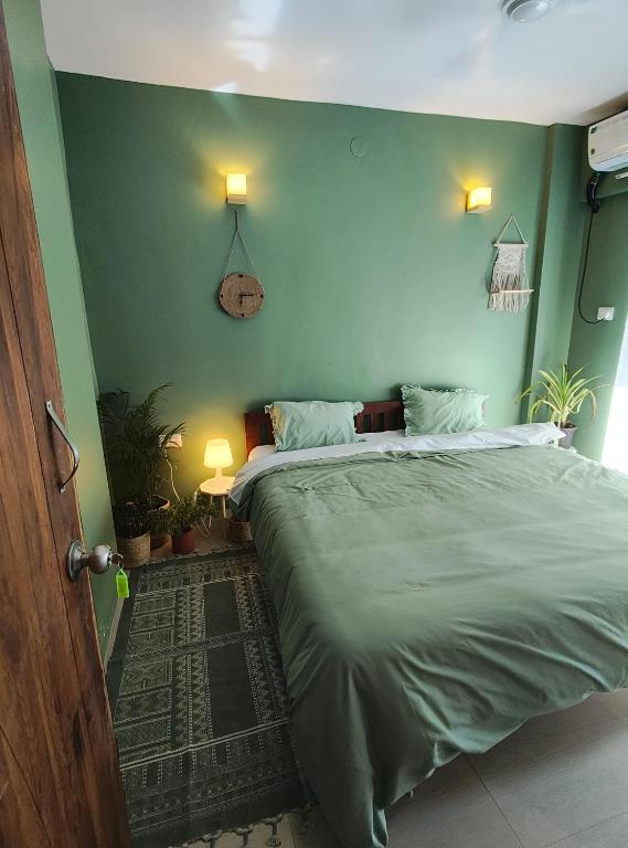a bedroom with a large bed with green walls at Blue Door Homes in Navi Mumbai
