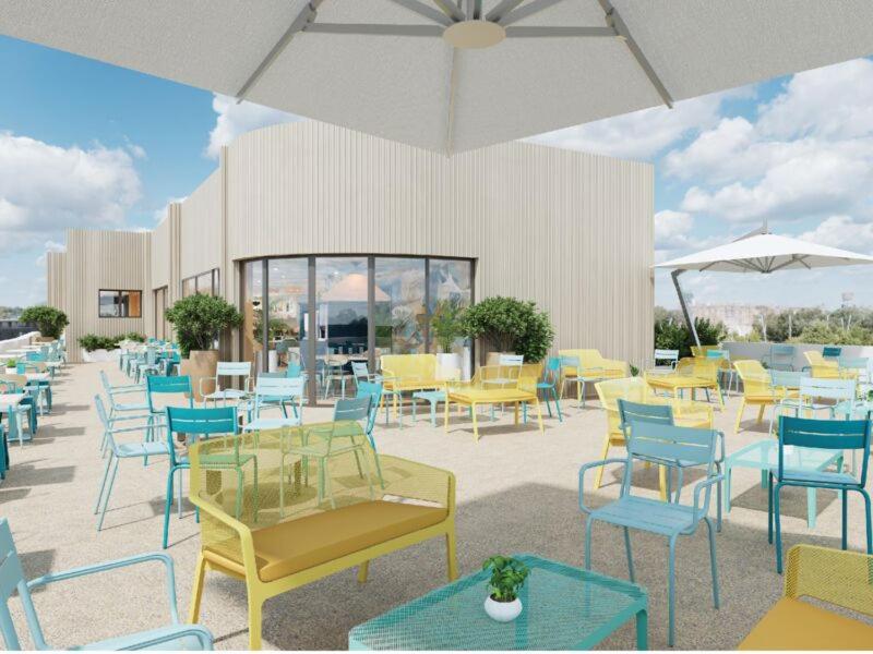 a patio with tables and chairs and an umbrella at All Suites Hôtel Chartres Centre Gare in Chartres