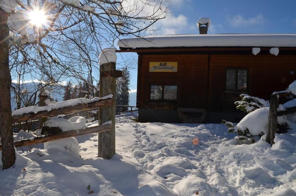 a snow covered cabin with the sun shining on it at Ferienhaus Kammerer in Haidberg