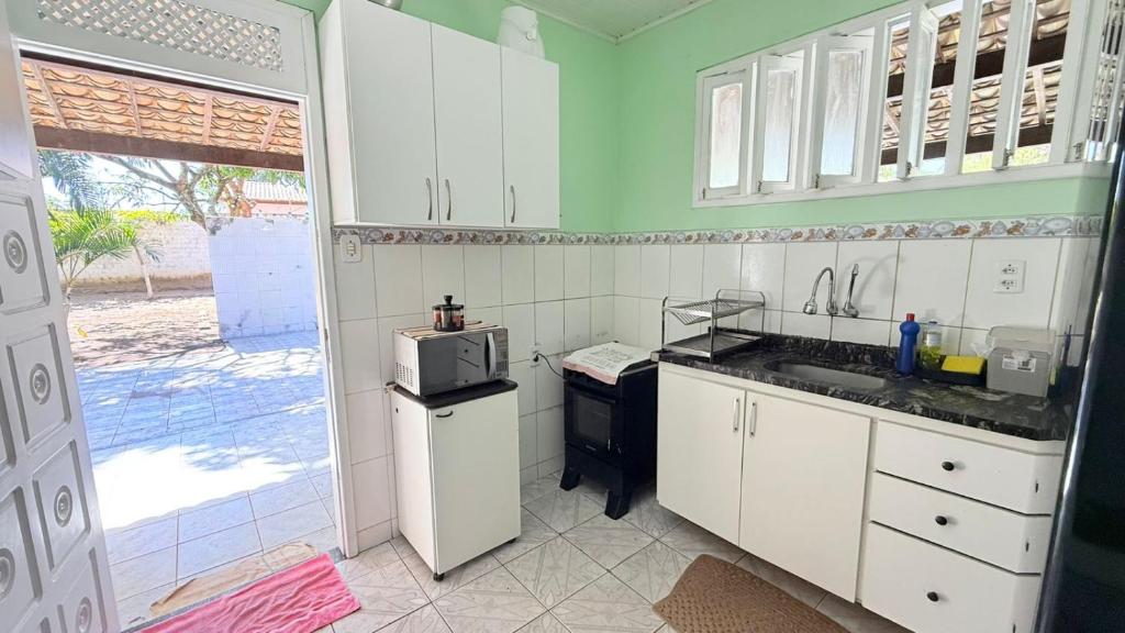 a kitchen with white cabinets and a microwave at Chácara das Mangueiras in Aracaju