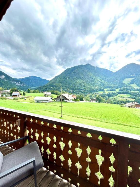 a balcony with a view of a field and mountains at Ecrin des anges in Vacheresse